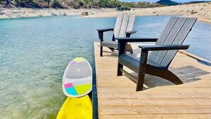 A wooden dock with two chairs and a yellow inflatable raft with a colorful ball attached.