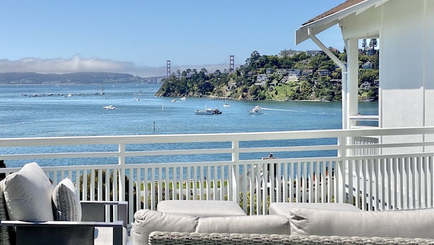 A balcony with wicker furniture and a white railing overlooking a bay with boats and a bridge in the distance. - Amazing Views and Walkable to Downtown! Historic 3/2 Home, Sleeps 8 (Tiburon)