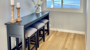 A room with a dark wooden table, two candles, and a vase with flowers. There are three upholstered chairs and a large window with a view of the ocean. - Amazing Views and Walkable to Downtown! Historic 3/2 Home, Sleeps 8 (Tiburon)