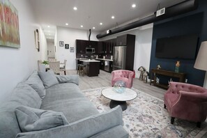 A living room with a grey sofa, a round coffee table, and two pink armchairs.