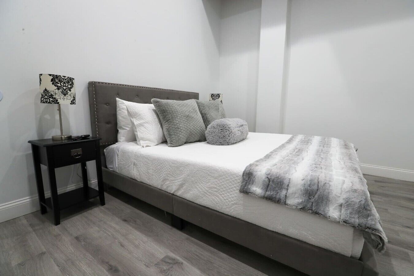 A bedroom with a bed, a nightstand, and a lamp.