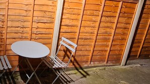 A wooden wall with a metal table and two metal chairs. - Maple House - Inviting 1-bed Apartment in London (London)