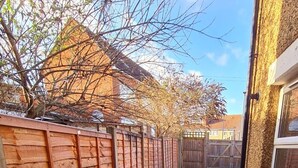 A wooden fence, a small garden area with potted plants, and a building with a window. - Maple House - Inviting 1-bed Apartment in London (London)