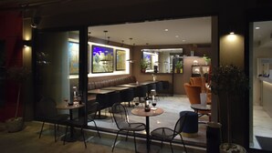 Un comedor interior moderno con mesas, sillas, un sofá y una barra.