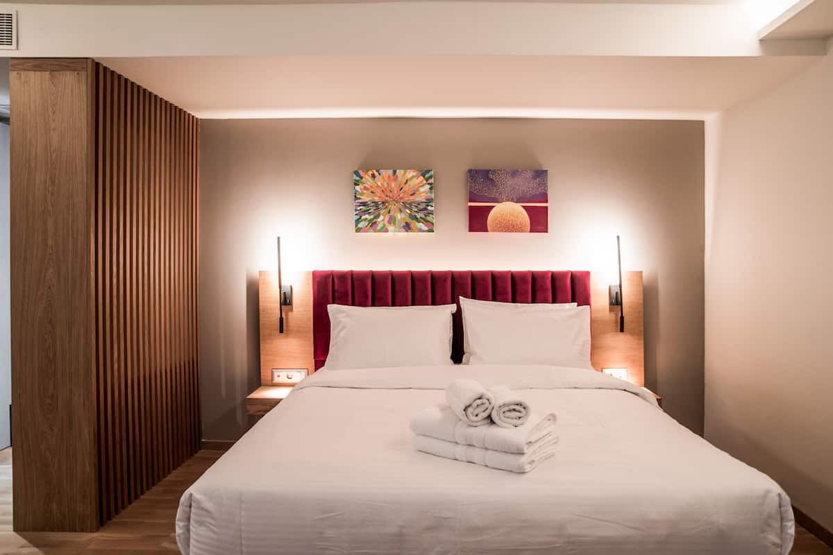 Una camera d'albergo con un letto grande, due lampade a parete e due quadri appesi al muro.