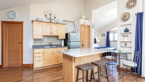 A modern kitchen with wooden cabinets, a stainless steel refrigerator, and a marble countertop. - Two-Bed Cabin – Breathtaking Fjord View at the Summit House. (Malahat)