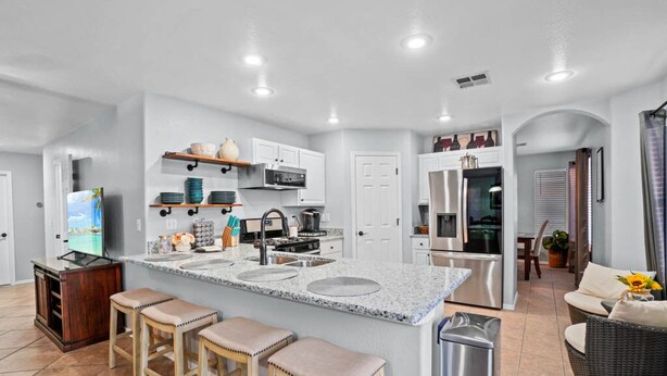 A modern kitchen with a central island, built-in appliances, and a dining area with a sofa and table. - Spacious 3 bedroom 2.5  bath with 3 living areas (Las Cruces)