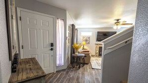 A hallway with a wooden table, a door, and a staircase leading to an upper level. - Spacious 3 bedroom 2.5  bath with 3 living areas (Las Cruces)