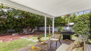 Un patio al aire libre con mobiliario de mimbre, una parrilla y un hogar para la chimenea.