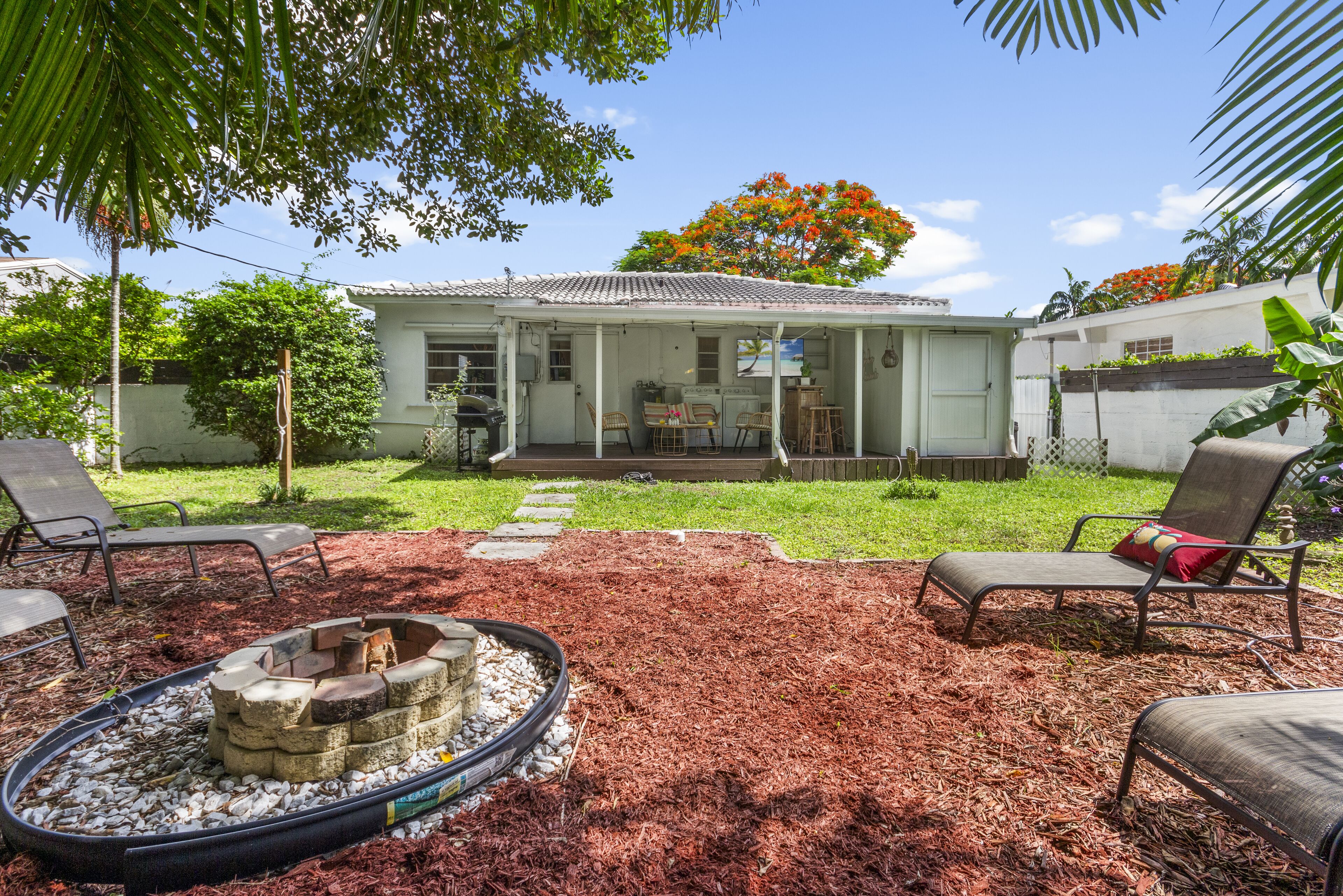 A house with a covered patio, outdoor seating, and a fire pit.