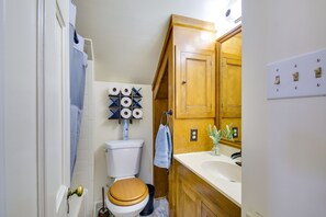 Un baño con inodoro, lavamanos, armarios de madera y un perchero para toallas.
