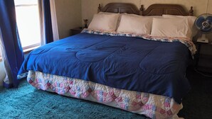 A bedroom with a bed, curtains, a nightstand, and a fan. - Experience the Peaceful Wonders of Nature Here (Baldwin)