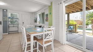 A modern kitchen with white cabinetry, a dining table with chairs, and a sliding glass door leading to an outdoor patio. - DOG-FRIENDLY, OUTDOOR POOL, DUPLEX BEACH HOUSE!! (Gulf Shores)