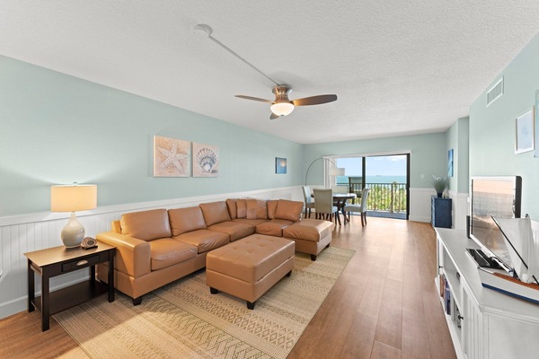 Modern and cozy living room with a leather sofa, warm lighting, and balcony access.