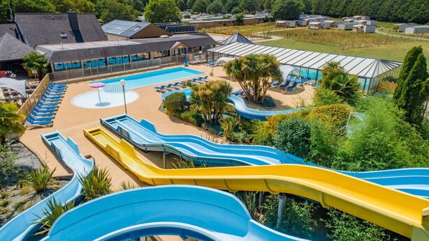 A water park with multiple slides, a pool, and lounge areas. - Camping familial 4* | Mobil-home + Accès piscine (Monterblanc)