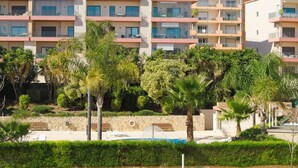 Ein mehrstöckiges Hotel mit Balkonen, einem Swimmingpool und üppiger Bepflanzung.