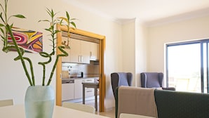 Ein modernes Wohnzimmer mit Esstisch, einer Couch und einer Küche im Hintergrund.