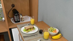 A compact kitchenette with a small fridge, a coffee maker, and a fruit bowl. - Palulu Flats (São Sebastião)