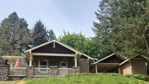 Un chalet doté d’un porche abrité, de piliers en pierre et d’un petit bâtiment attenant.