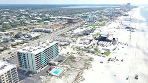 Vue aérienne d’une ville côtière avec une plage, des immeubles de grande hauteur et un parking.