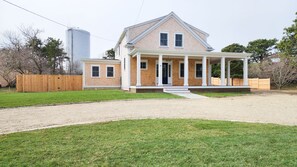 A two-story house with a covered porch and a fenced yard. - Katama home with pool and on bike path! Walk to Edgartown and South Beach! (Edgartown)