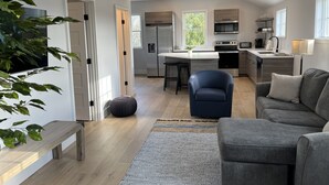 Ett modernt kök med en central köksö, inbyggda vitvaror och en matplats.