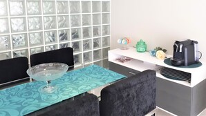 A modern kitchen with a white countertop, black chairs, a glass coffee table, and a backsplash with square tiles.