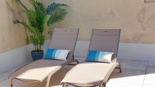Two lounge chairs with cushions, a potted plant, and a concrete floor.