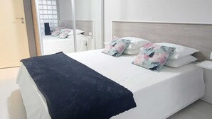 A bedroom with a bed, a mirror, and a wardrobe.