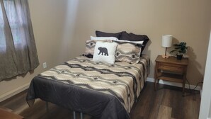 Une chambre à coucher avec un lit, une table de chevet, une lampe et une plante en pot.
