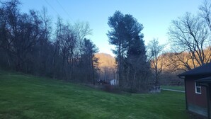 Un champ herbeux avec des arbres et un petit bâtiment.