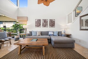 Un salon moderne avec un canapé d’angle, une table basse en bois et un tapis à motifs.