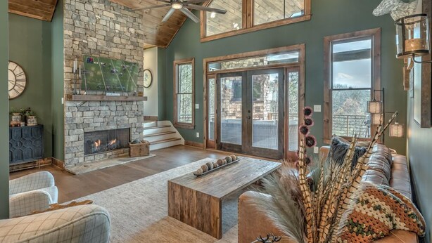 A spacious living room with a stone fireplace, a large television, and a cozy seating area with a couch and a coffee table. - Whiskey Hollow Lodge - Mountain Views | Outdoor Living | Hot Tub (Morganton)