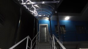 Una escalera con barandillas metálicas que conduce a un cuarto con pared azul y una puerta al final.