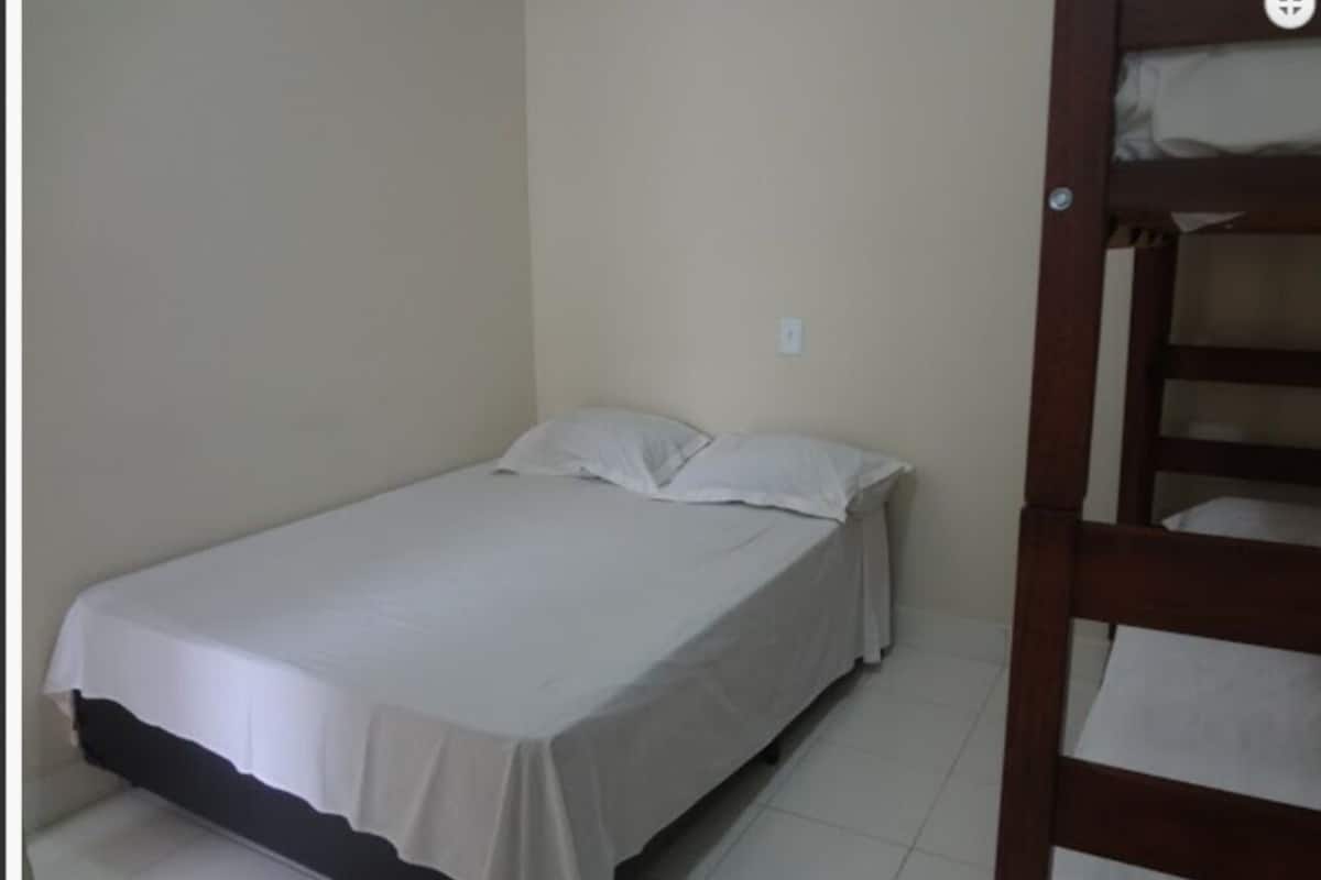 A small, single-bed room with a wooden bunk bed against the wall.