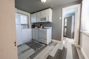 A kitchen with white cabinets, a microwave, a stove, and a coffee maker. - The Nest Apt B (West Sacramento)