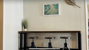 Una cuina amb tres tamborets de bar, una planta en test i un quadre a la paret.