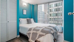 Ein Schlafzimmer mit einem Bett, einem Fenster mit Jalousien und einer Tür.