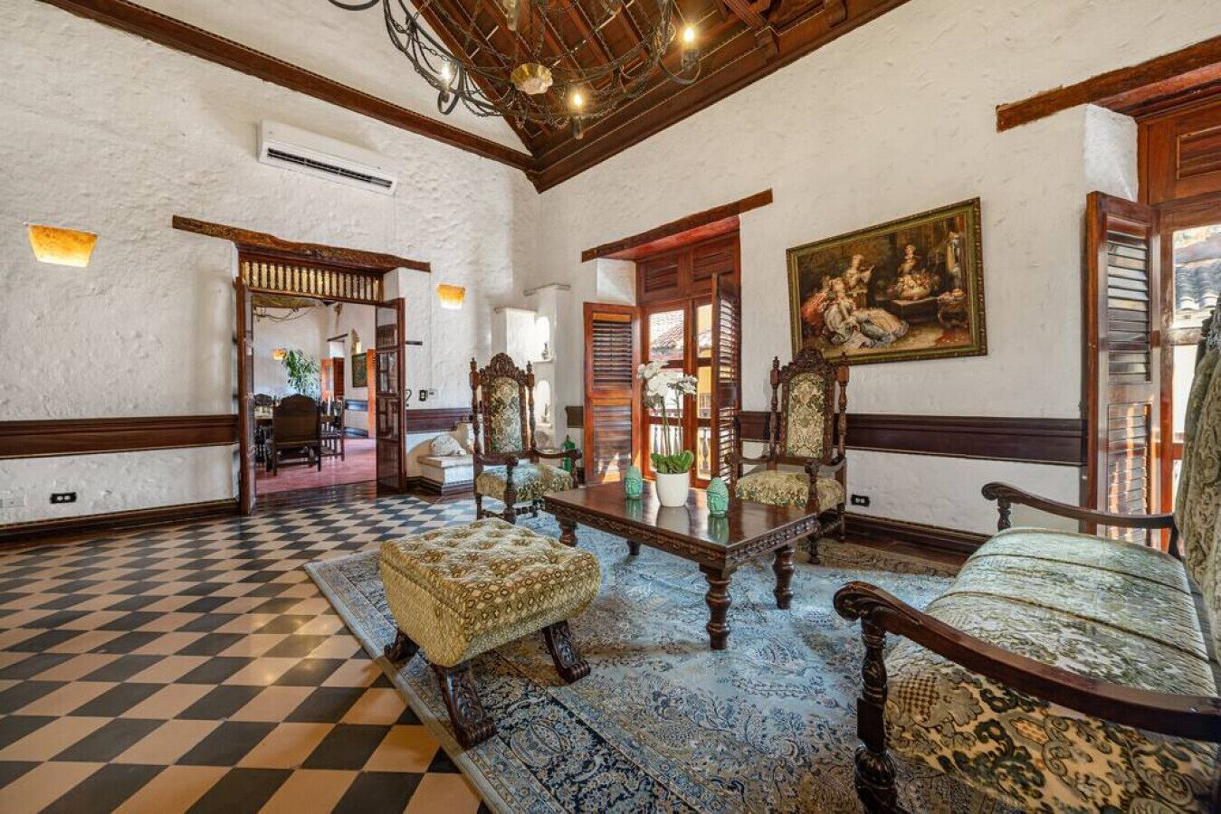 A spacious lobby with a checkered floor, ornate furniture, and a large painting on the wall.