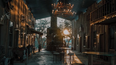 A rustic interior with wooden walls, a stone fireplace, and a chandelier.