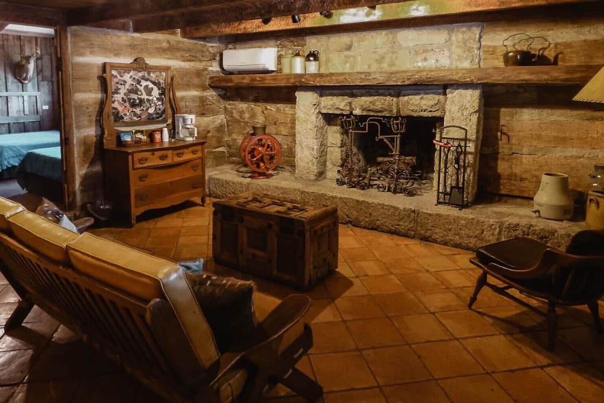 Um interior rústico com lareira de pedra, móveis de madeira e um detalhe decorativo na parede.
