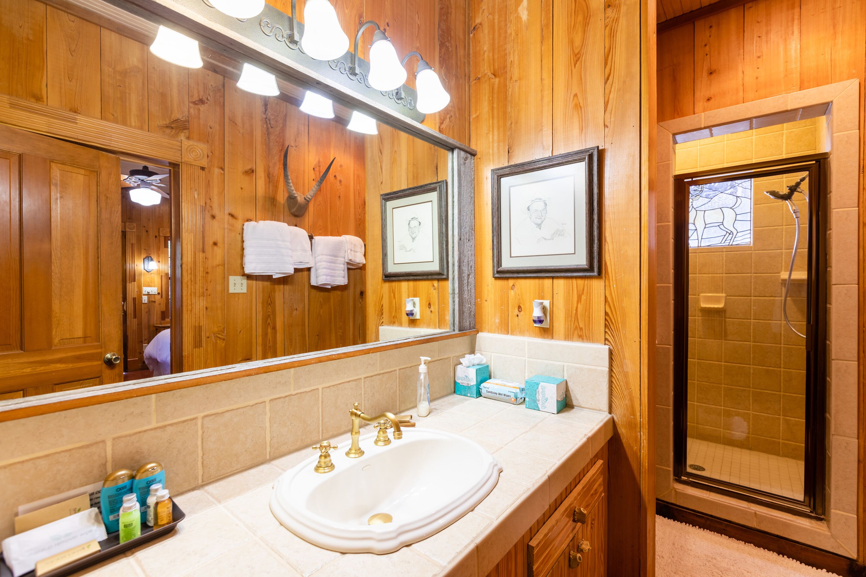 Un baño de madera con un espejo grande, un lavabo y una ducha.