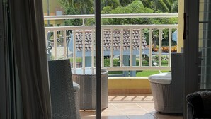 Een kamer met uitzicht op een balkon, rieten meubilair en een betegelde vloer.