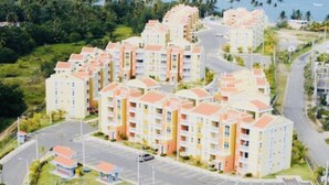 Een wooncomplex met meerdere appartementen gebouwen, een tennisbaan en uitzicht op de oceaan.