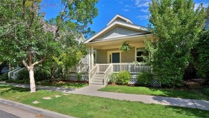 A two-story house with a front porch, a small front yard, and a street view. - Modern Comfort in Central Park: 4BR Home in Denver (Denver)