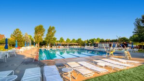 A swimming pool with lounge chairs and umbrellas, surrounded by trees and a covered area. - Modern Comfort in Central Park: 4BR Home in Denver (Denver)