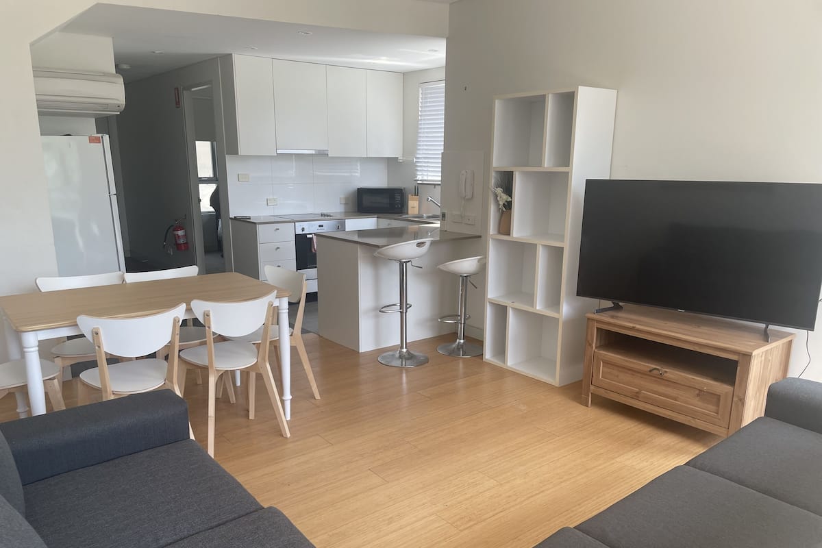 Una cocina moderna con armarios blancos, un microondas y una zona de comedor con mesa y sillas.