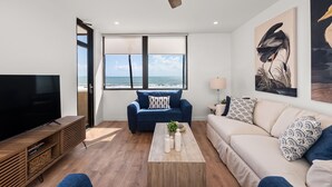 Una sala de estar moderna con un televisor grande, un sofá azul, un sofá beige y una mesa de centro de madera.