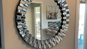A round mirror with a reflective surface mounted on a wall.