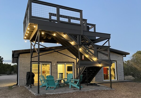 Un bâtiment à deux étages doté d’un patio couvert comprenant un espace de détente en plein air et un escalier.